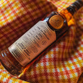 Bouteille de Single Malt Scotch Whisky Caol Ila 20 ans Connoisseurs Choice Gordon & MacPhail posée sur une étoffe de Harris Tweed
