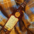 Bouteille de Single Malt Scotch Whisky Highland Park 22 ans Connoisseurs Choice Gordon & MacPhail posée sur une étoffe de Harris Tweed