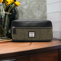 Grande trousse de toilette Harris Tweed® au motif chevron marron et vert posée sur une console en bois rustique.