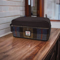 Grande trousse de toilette Harris Tweed® au motif tartan marron, bleu et gris posée sur une étagère en bois brut.