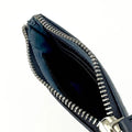 Vue de l'intérieur du petit porte-monnaie Harris Tweed® montrant la doublure textile et les compartiments de rangement.