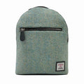 Vue de face du petit sac à dos Harris Tweed® montrant le rabat en laine chevron turquoise, la poche zippée horizontale et l'étiquette de certification Orb Mark.