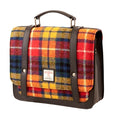 Vue de face de la petite sacoche Harris Tweed® au tartan jaune, bleu et rouge avec poignée et sangles en cuir végan gris sur fond blanc.