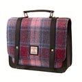 Vue de face de la petite sacoche Harris Tweed® tartan rose, bleu et violet avec poignée et sangles en cuir végan gris anthracite sur fond blanc.