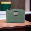 Petite trousse de toilette Harris Tweed® au motif chevron bleu turquoise et vert posée sur un meuble de toilette en bois.