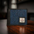 Portefeuille 3 volets Harris Tweed® au motif chevron bleu marine et noir posé sur une surface en bois sombre.