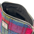 Vue intérieure du sac bandoulière carré Harris Tweed® montrant la doublure noire, la poche zippée et l'étiquette d'authenticité Orb Mark.