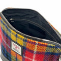 Vue intérieure du sac bandoulière carré Harris Tweed® montrant la doublure noire, la poche zippée et l'étiquette d'authenticité Orb Mark.