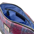 Vue intérieure du sac bandoulière carré Harris Tweed® montrant la doublure bleu clair, la poche zippée et l'étiquette d'authenticité Orb Mark.