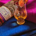 Bouteille couchée de Single Malt Scotch Whisky Bunnahabhain 11 ans Gordon & MacPhail avec tissu Harris Tweed et verre glencairn