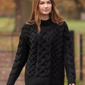 Portrait d'une femme portant le pull jumper Merston noir, soulignant la qualité du tricot en laine mérinos et la structure des torsades complexes de style Aran d'Irlande.