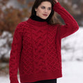 Portrait d'une femme en extérieur sous la neige portant le pull jumper rouge, un vêtement en tricot de laine mérinos robuste et chaud de style Aran d'Irlande.