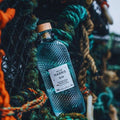 Bouteille de Gin Botanique London Dry Isle of Harris Gin et posée sur des filets de pêche