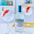 Bouteille de Gin Botanique Distilled Gin Tobermory Hebridean Gin et verres de cocktails posés sur une table en bois blanc