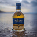 Bouteille de Single Malt Scotch Whisky Kilchoman Machir Bay posée sur le sable mouillé d'une plage