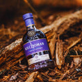 Bouteille de Single Malt Scotch Whisky Kilchoman Sanaig posée sur un tapis d'écorces dans la forêt
