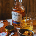 Bouteille de Single Malt Scotch Whisky Old Pulteney 10 ans Flotilla posée sur une table avec deux verres et une boîte de caviar ouverte